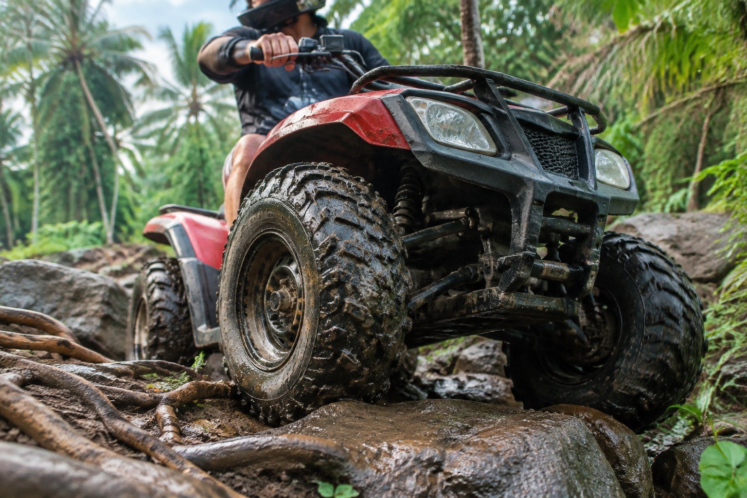 ATV wheels navigating wet rocks and roots on a Bali trail